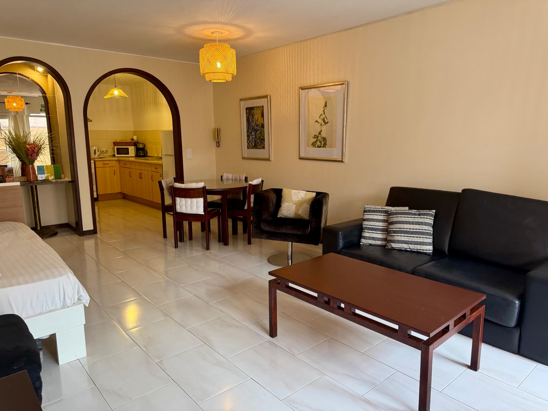 Family Villa dining nook with glass table, yellow pendant light and kitchen arch