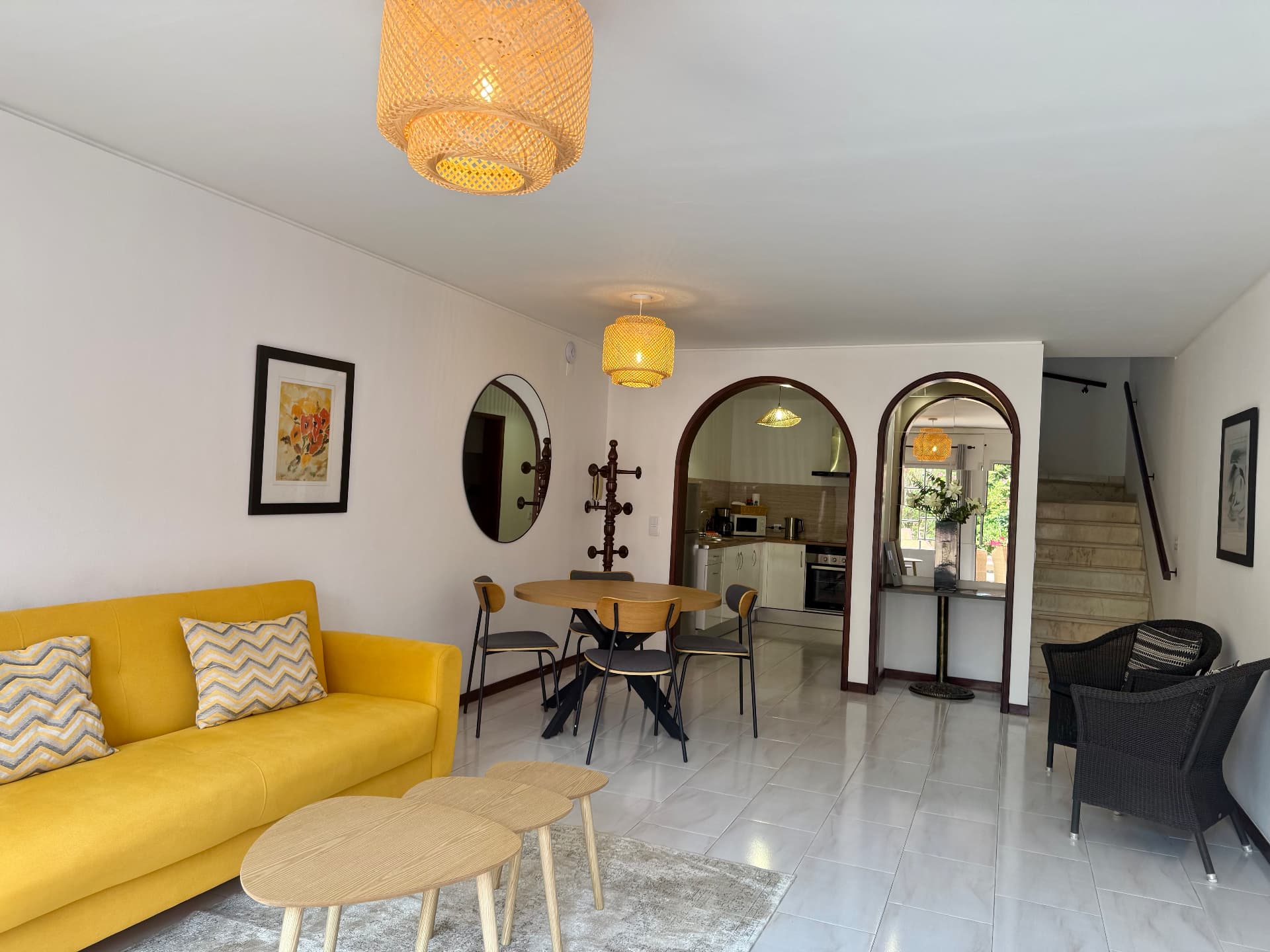 Comfort Villa living area with yellow sofa, black wicker armchairs and marble staircase